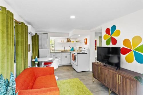 a living room with an orange couch and a kitchen at That 70’s Themed Apt Close to Coffee, Food + Shops in Tampa