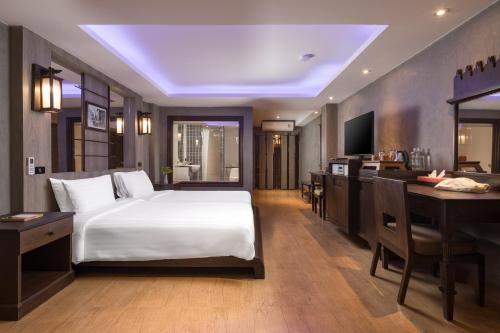 a bedroom with a bed and a desk and a television at Panviman Resort Koh Phangan in Thong Nai Pan Noi