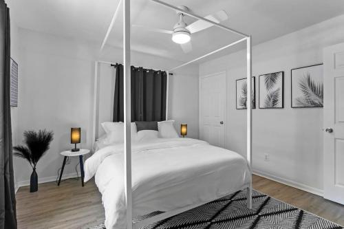 a white bedroom with a large white bed with a mirror at Zebra House - Close 2 all TampaBay has to offer in Tampa