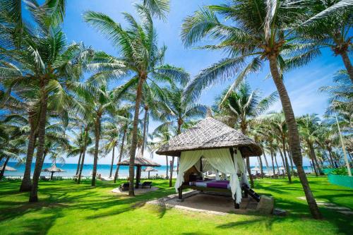 a hammock on the beach with palm trees at Pandanus Resort in Mui Ne