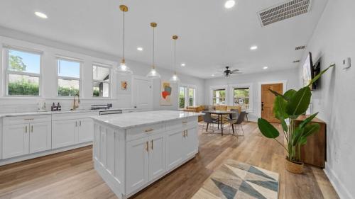 a kitchen with white cabinets and a large white island at Mid-Century Modern Retreat by Coffee, Food + Shops in Tampa