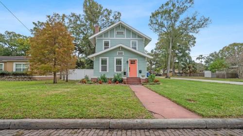 a blue house with a red door in a yard at Spacious Modern Farmhouse w/ Private Patio & BBQ! in Tampa