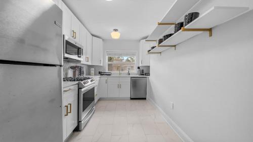 a white kitchen with white cabinets and appliances at Spacious Modern Farmhouse w/ Private Patio & BBQ! in Tampa