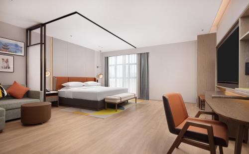a bedroom with a bed and a couch and a tv at Hilton Garden Inn Xingyi Orange Hill Plaza in Xingyi
