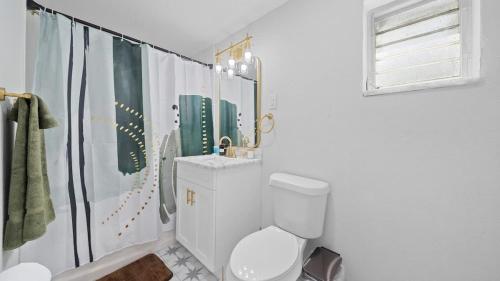 a white bathroom with a toilet and a sink at Modern-Retro Themed Home Close to Coffee + Food! in Tampa