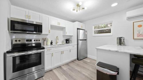 a kitchen with stainless steel appliances and white cabinets at Modern-Retro Themed Home Close to Coffee + Food! in Tampa