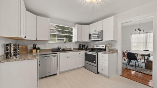 a white kitchen with white cabinets and a table at Modern Moroccan Villa w/ Firepit, BBQ + Game Room! in Tampa