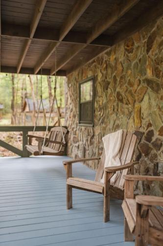 two rocking chairs on a porch with a stone wall at Modern Cabin with Luxury Gym, Firepit + Game Room! in Blue Ridge