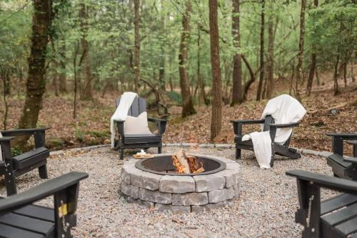 three chairs and a fire pit in the woods at Modern Cabin with Luxury Gym, Firepit + Game Room! in Blue Ridge