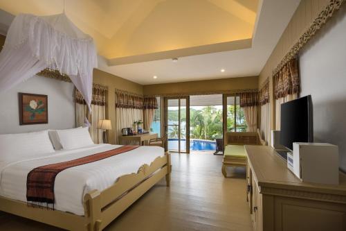a bedroom with a bed and a desk and a television at Panviman Resort Koh Phangan in Thong Nai Pan Noi