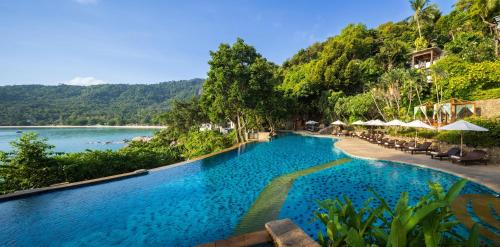 a swimming pool next to a body of water at Panviman Resort Koh Phangan in Thong Nai Pan Noi