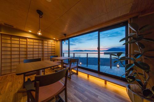 a room with tables and a large window with a view at Ryokan Beniayu in Nagahama