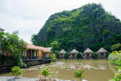 a group of houses in front of a mountain at Hang Mua Peaceful Retreat in Xuân Sơn