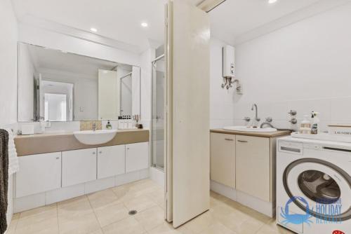 a white bathroom with a sink and a washing machine at Coastal Canal Retreat in Mandurah in Mandurah