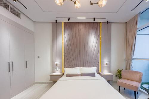 a bedroom with a large white bed and a chair at Damac Hills Carson studio on Golf Course in Dubai Marina