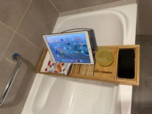 a tablet computer sitting on a wooden shelf on a bath tub at Damac Hills Carson studio on Golf Course in Dubai Marina