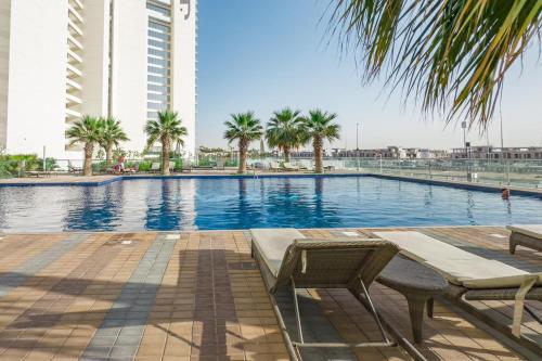 a swimming pool with palm trees and a building at Designer 1BR I Golf View I Comfortably Sleeps 4 in Dubai