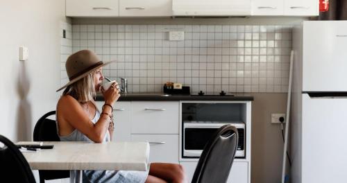 a woman sitting at a table in a kitchen drinking from a cup at BIG4 Breeze Holiday Parks - Katherine in Katherine