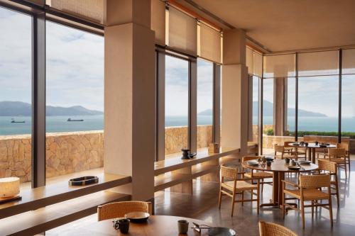 a restaurant with tables and chairs and large windows at Alila Dong'Ao Island Zhuhai in Zhuhai