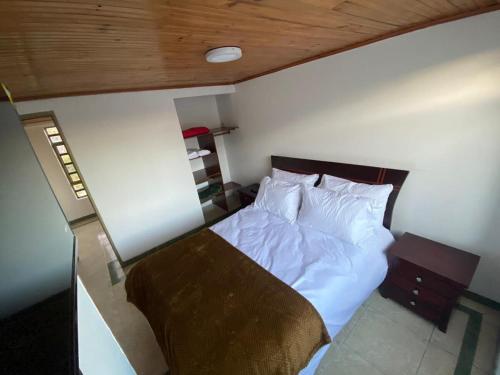 a bedroom with a bed with white sheets and a wooden ceiling at Casa Santa María in Bogotá