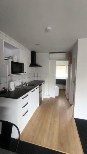 a kitchen with white cabinets and a wooden floor at Pakuranga Motor Lodge in Auckland