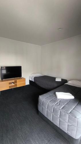a hotel room with two beds and a flat screen tv at Pakuranga Motor Lodge in Auckland