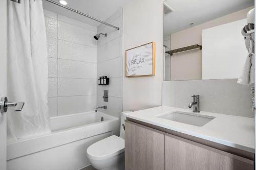a white bathroom with a sink and a toilet at The Getaway Next to Stampede 2BR Suite Downtown in Calgary