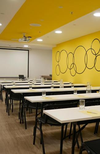 a classroom with rows of tables and a yellow wall at The Place Hotel in Quito