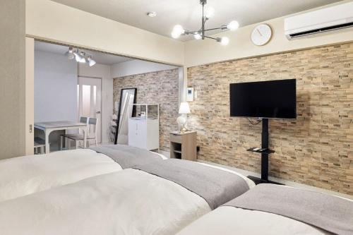a bedroom with three beds and a tv on a brick wall at Make Your Hotel Susukino A in Sapporo