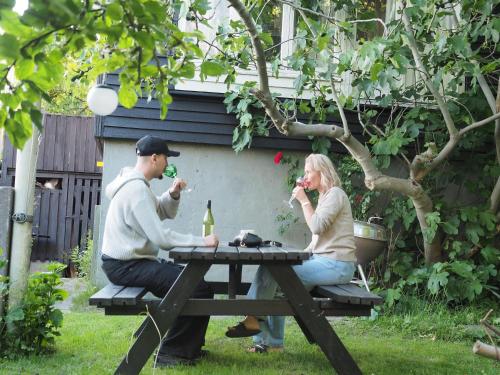 a man and woman sitting at a picnic table drinking wine at Villa Rosa, dobblebed, own kitchen, own bath and own entrance in Copenhagen