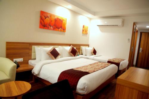 a hotel room with two beds and a table at Le Roi Jammu - Near Jammu Railway Station in Jammu
