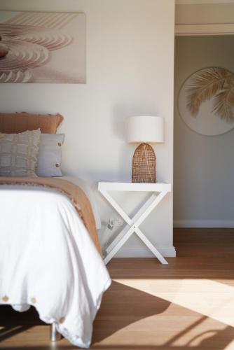 a bedroom with a bed and a table with a lamp at Diggers Beach Villa Coffs Harbour in Coffs Harbour