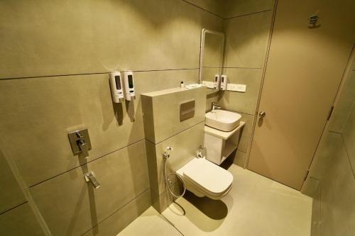 a bathroom with a toilet and a sink and a phone at Hotel Homansh by Goldsum in Lucknow