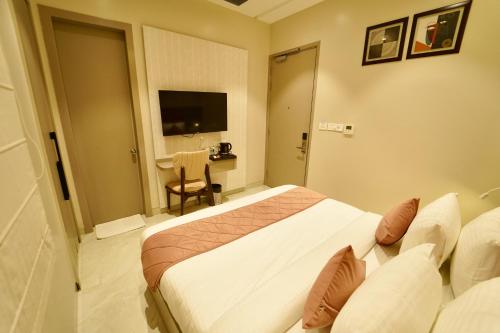 a hotel room with a bed and a chair and a table at Hotel Homansh by Goldsum in Lucknow