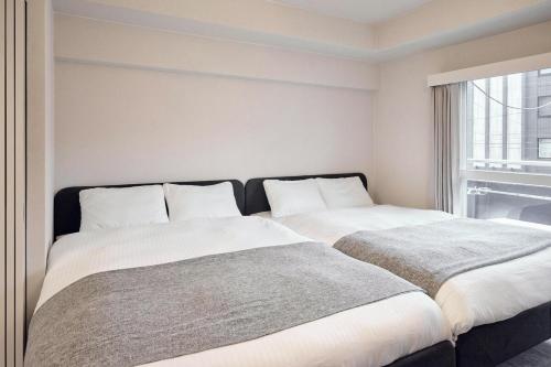 two beds sitting next to each other in a bedroom at Stylish Room Near Susukino 2 Beds 205 in Sapporo