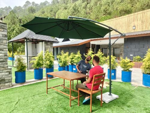 two people sitting at a table under an umbrella at Kasauli Hill crest By Xaria Luxury Studio Apartment in Kasauli