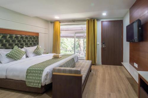 a hotel room with a bed and a television at Alps Resort in Dalhousie