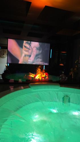 a swimming pool with a tv and a tub with a fire at Private Spa Penthouse in Skopje