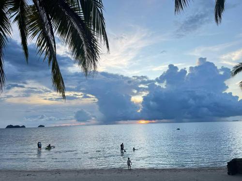 a group of people in the water at the beach at MJOY Resort in Taling Ngam Beach