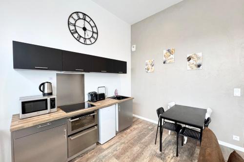 une cuisine avec une table et une horloge au mur dans l'établissement Joli T2 esprit loft design & confort, à Lorient
