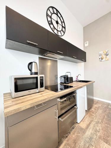 une cuisine avec un micro-ondes et une horloge au mur dans l'établissement Joli T2 esprit loft design & confort, à Lorient