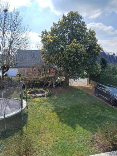 - une vue sur une cour avec un arbre et une voiture dans l'établissement Maison T3 avec jardin 5 minutes de Vannes, à Saint-Avé