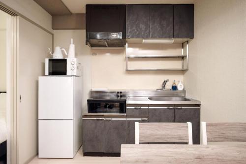 a kitchen with a white refrigerator and a microwave at Make Your Hotel Susukino D in Sapporo
