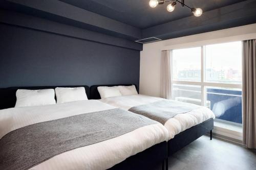 a bedroom with a large bed with a large window at Make Your Hotel Susukino D in Sapporo
