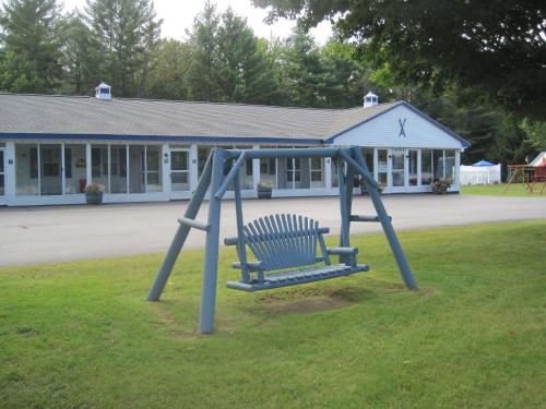 a blue bench sitting in the grass in front of a building at North Colony Motel and Cottages in Bartlett