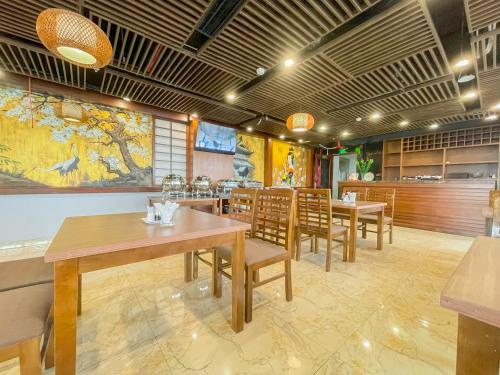 a restaurant with tables and chairs and a large painting on the wall at Azumaya Hotel Dao Tan in Hanoi