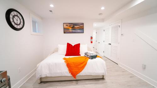 a bedroom with a bed with red pillows and a clock at Cozy 1BR 1BA Retreat in a Private DC Basement in Washington, D.C.