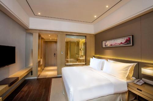 a bedroom with a large white bed and a television at Crowne Plaza Hefei Rongqiao by IHG in Hefei