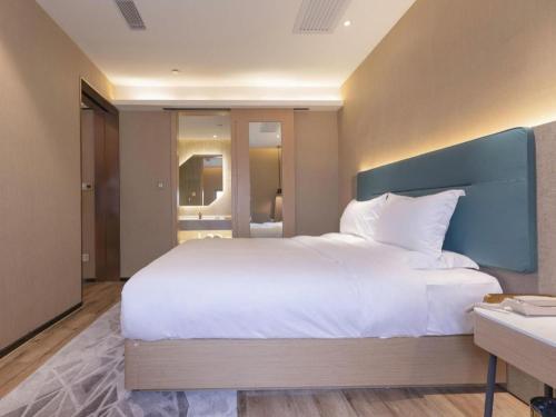 a bedroom with a large white bed with a blue headboard at ZMAX Hotels Shenzhen Lianhuacun Metro Station in Shenzhen