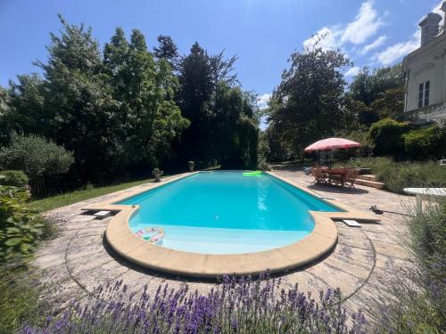 - une piscine dans un jardin avec une table et un parasol dans l'établissement Chateau La Palue, à Coutras